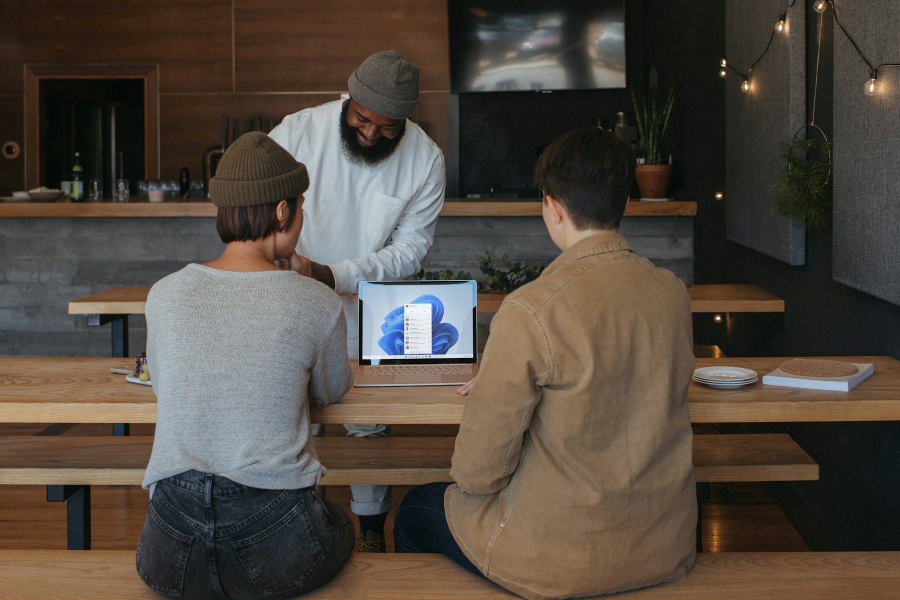 Three people meeting around a laptop in a welcoming workspace