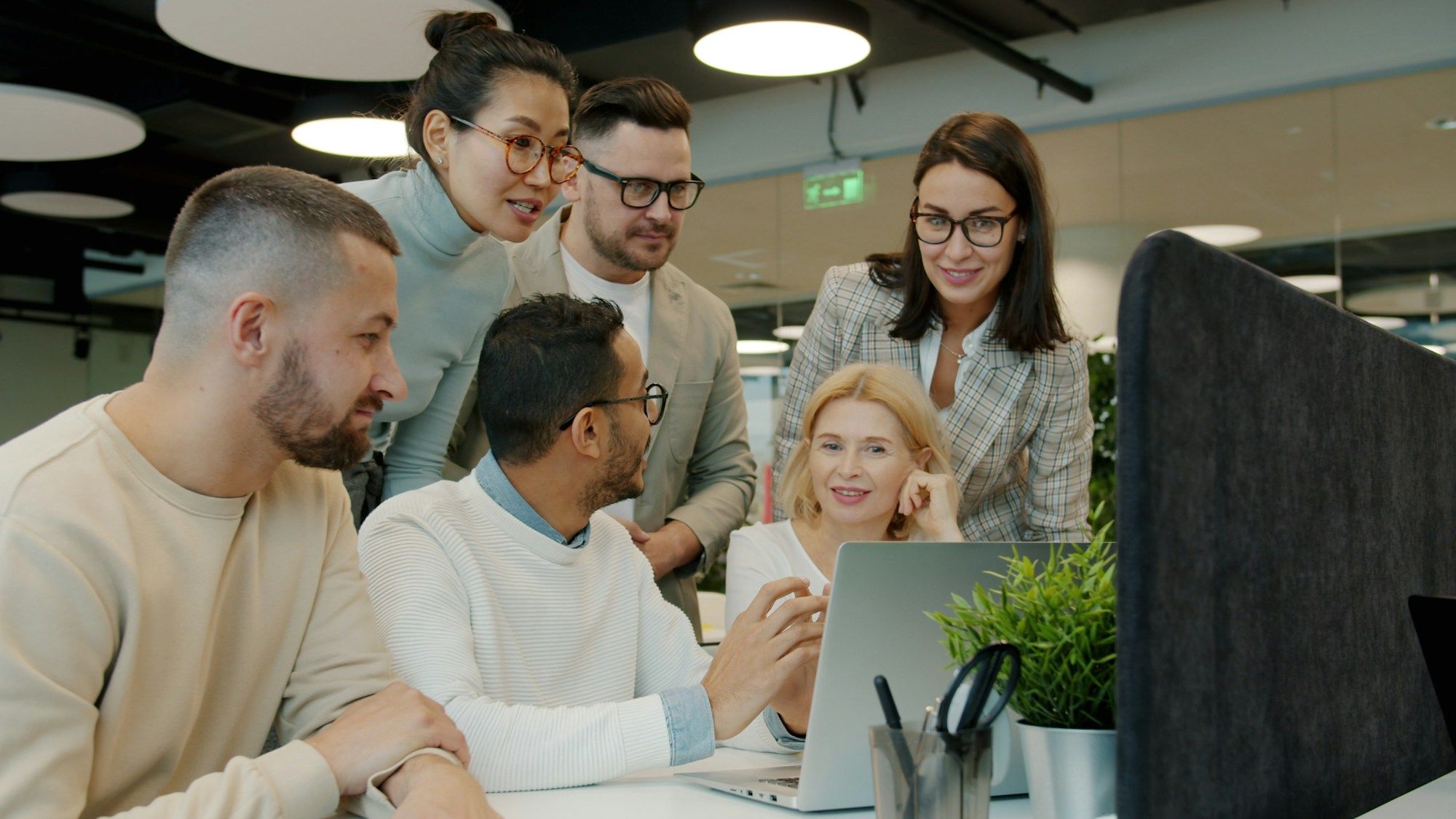 A diverse team collaborating around a computer in a modern office